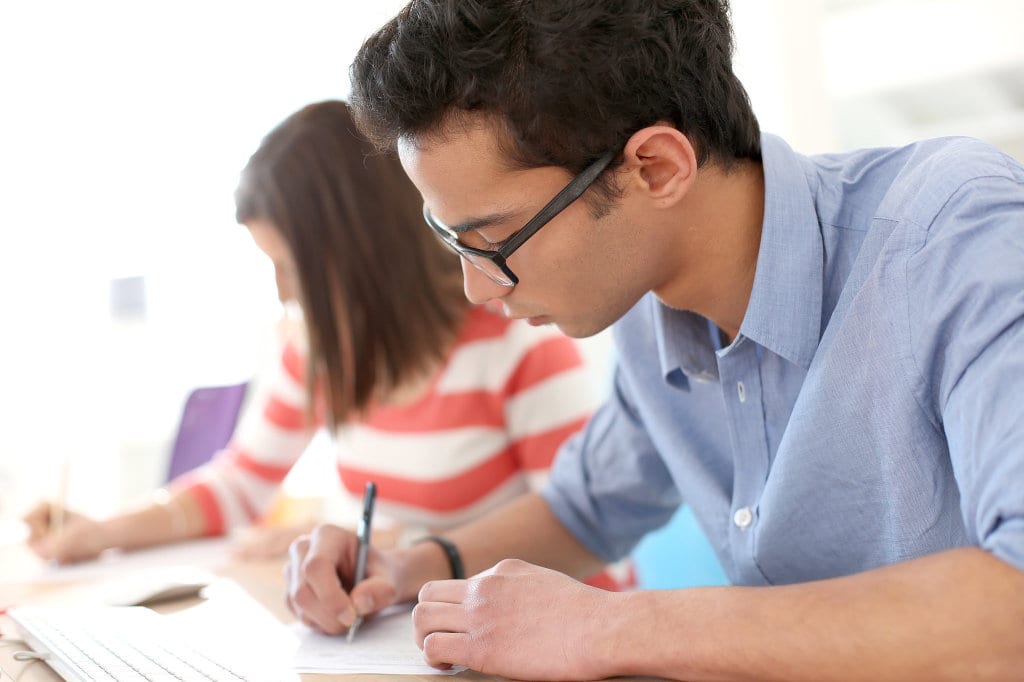 Students studying together with notebooks and textbooks, collaborating on course planning and high-school transcript preparation for college admissions.